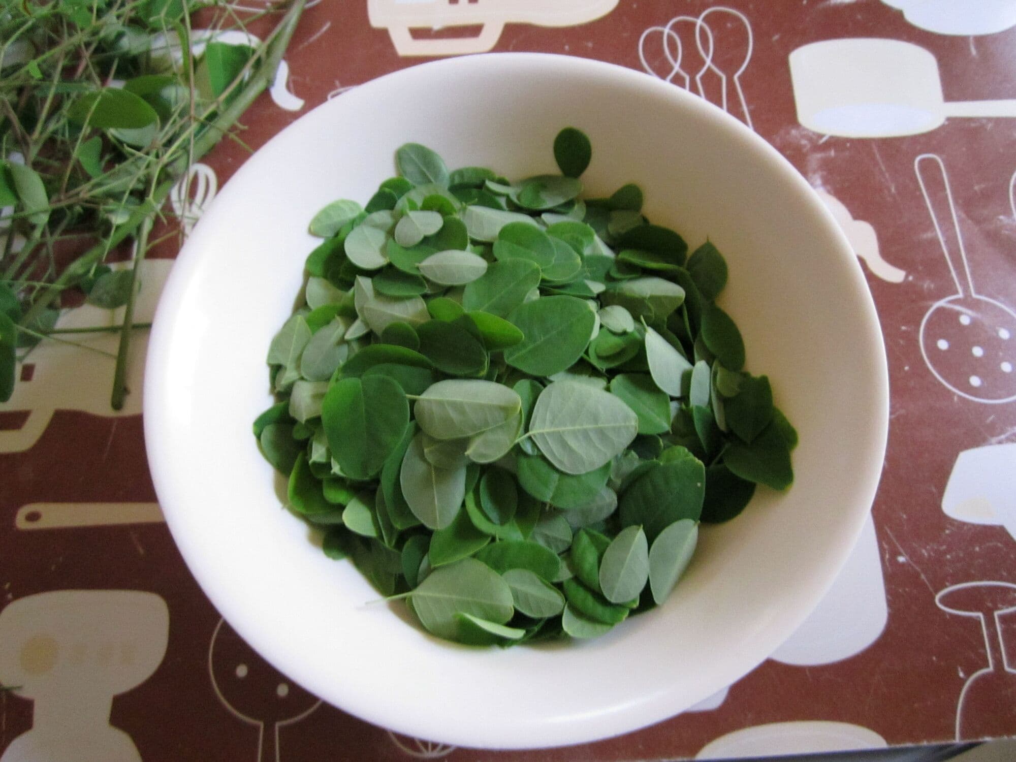 Fresh moringa leaves in a white bowl