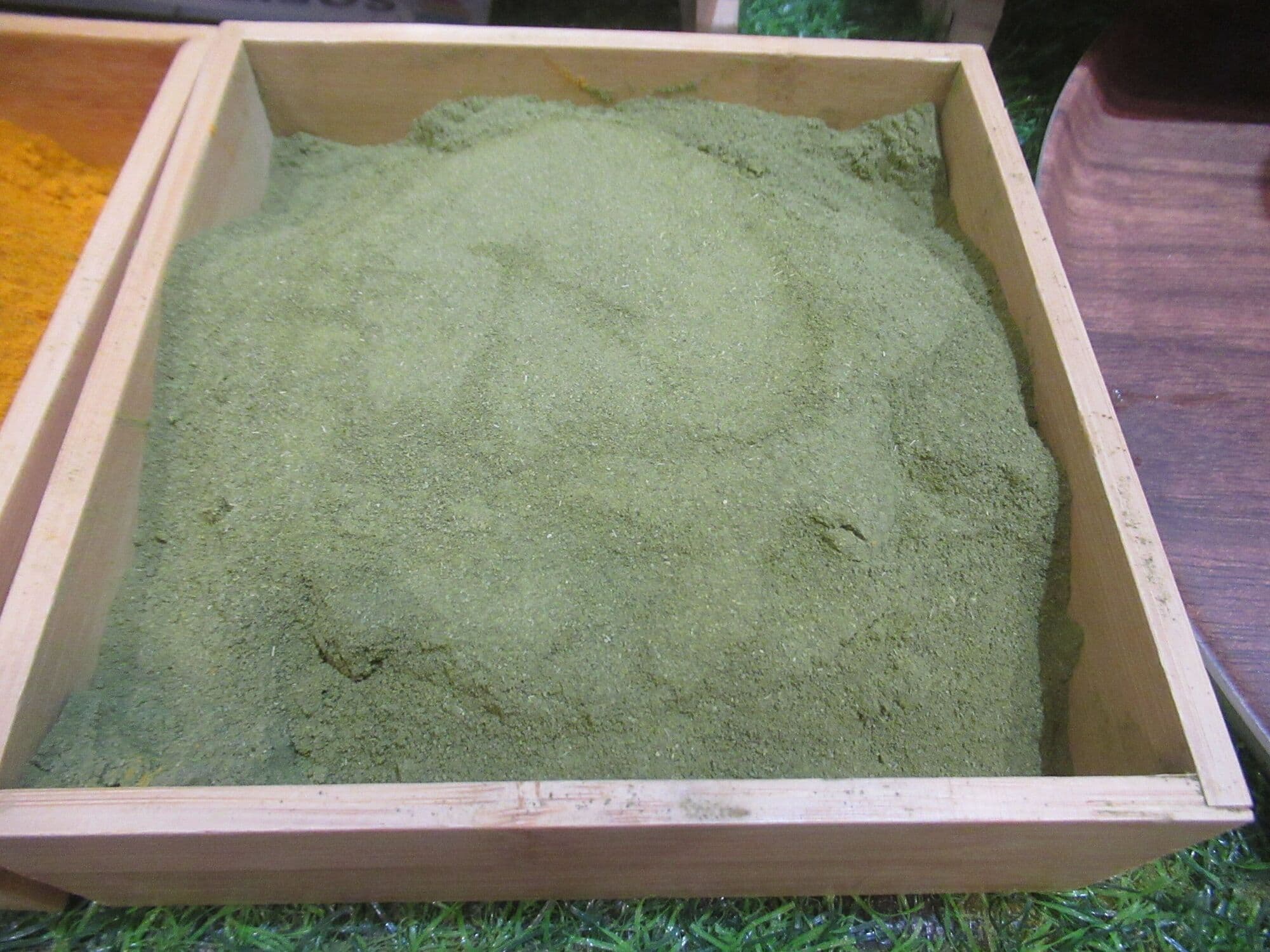 A wooden tray of moringa leaf powder